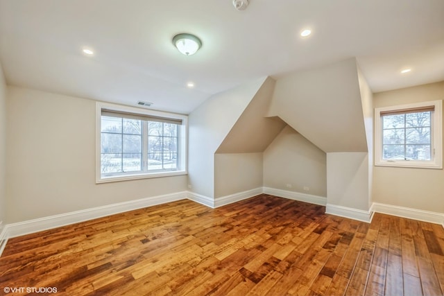 additional living space featuring hardwood / wood-style flooring, a healthy amount of sunlight, and lofted ceiling