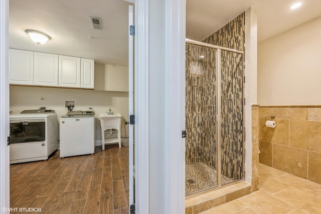 laundry room with cabinets, washing machine and dryer, and tile walls