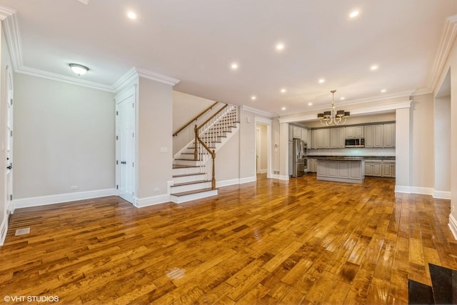 unfurnished living room featuring hardwood / wood-style flooring, a chandelier, and ornamental molding