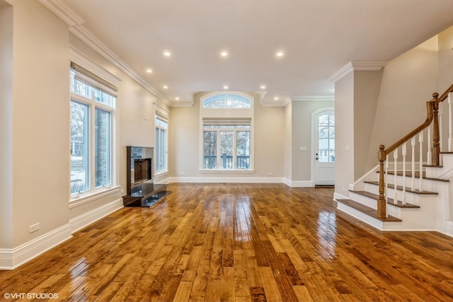 unfurnished living room featuring hardwood / wood-style floors, ornamental molding, and a premium fireplace