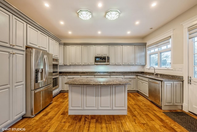 kitchen with gray cabinetry, sink, light hardwood / wood-style floors, appliances with stainless steel finishes, and a kitchen island