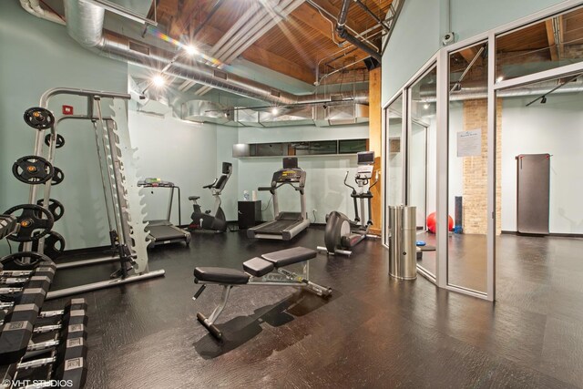 exercise room featuring wooden ceiling and high vaulted ceiling