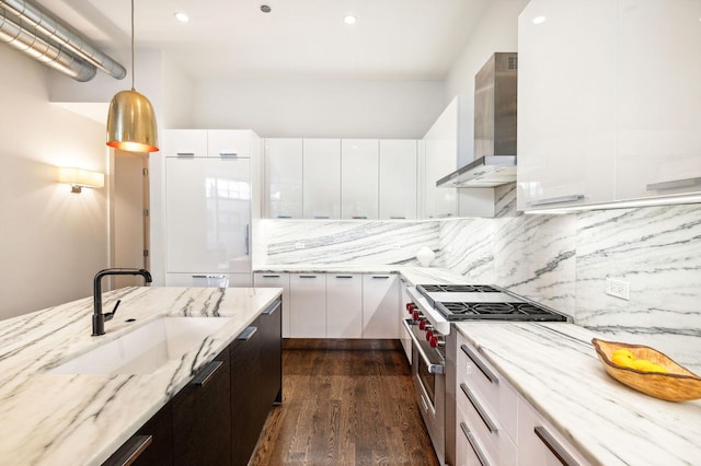 kitchen featuring white cabinetry, high end stainless steel range oven, wall chimney exhaust hood, and sink