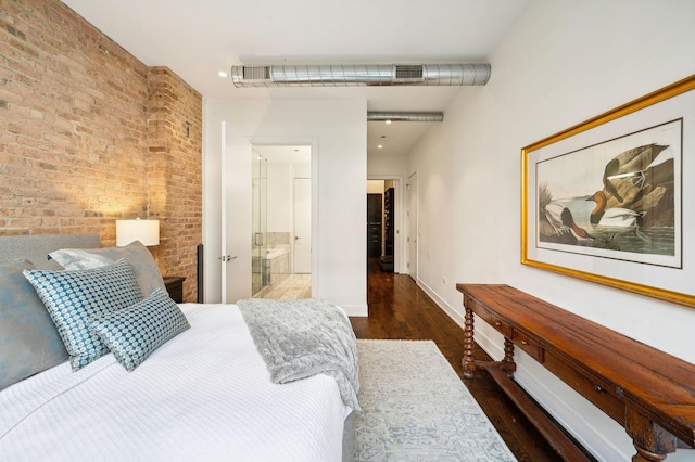 bedroom featuring ensuite bathroom, brick wall, and dark hardwood / wood-style floors