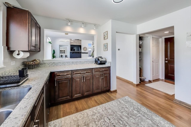 kitchen featuring light stone countertops, dark brown cabinets, light hardwood / wood-style floors, and sink