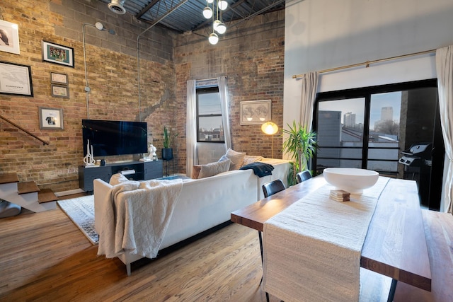 living room featuring hardwood / wood-style flooring, a high ceiling, and brick wall