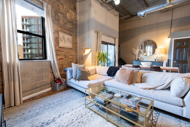 living room featuring a towering ceiling, brick wall, and hardwood / wood-style flooring