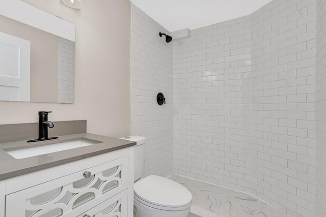 bathroom with vanity, toilet, and tiled shower