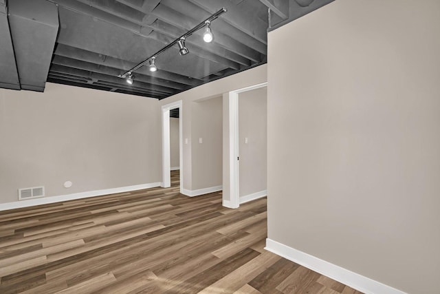 basement with hardwood / wood-style floors and track lighting