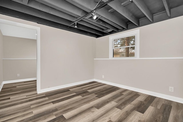 basement with hardwood / wood-style floors and track lighting