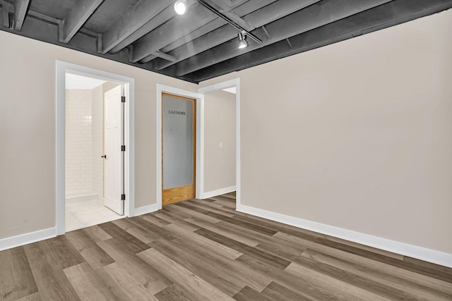 basement with track lighting and hardwood / wood-style flooring