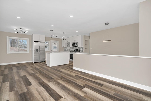 kitchen featuring backsplash, dark wood-type flooring, a kitchen island, white cabinetry, and stainless steel appliances