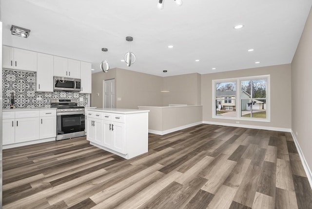 kitchen with decorative light fixtures, decorative backsplash, white cabinetry, and stainless steel appliances