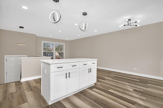 kitchen featuring decorative light fixtures, a kitchen island, white cabinetry, and hardwood / wood-style flooring