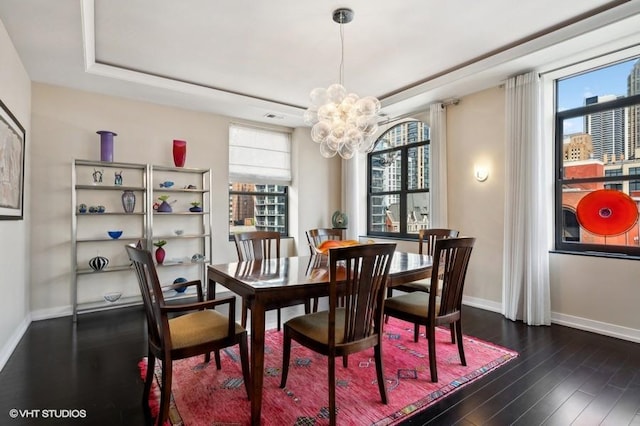 dining area featuring dark hardwood / wood-style flooring, a tray ceiling, an inviting chandelier, and a wealth of natural light