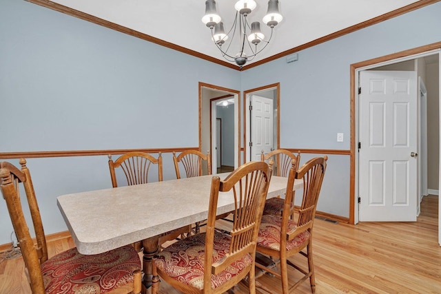 dining space with light hardwood / wood-style flooring, an inviting chandelier, and crown molding