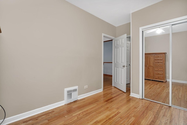 unfurnished bedroom with light wood-type flooring and a closet