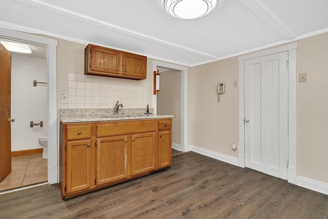 kitchen with dark hardwood / wood-style flooring, sink, ornamental molding, and backsplash