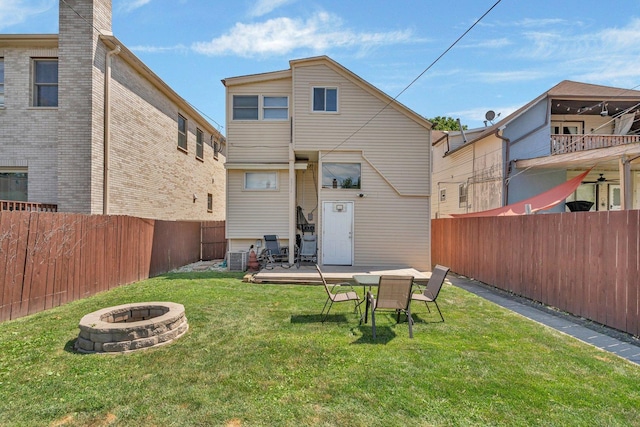 back of property featuring an outdoor fire pit and a lawn