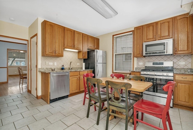 kitchen featuring decorative backsplash, light stone counters, light tile patterned floors, and stainless steel appliances