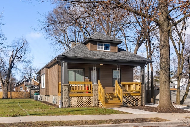 view of front facade with cooling unit, covered porch, and a front yard