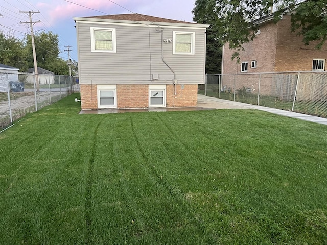 back house at dusk featuring a yard