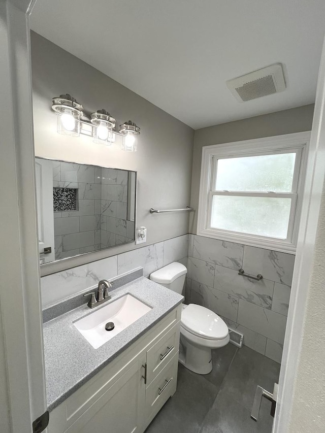 bathroom featuring vanity, toilet, and tile walls