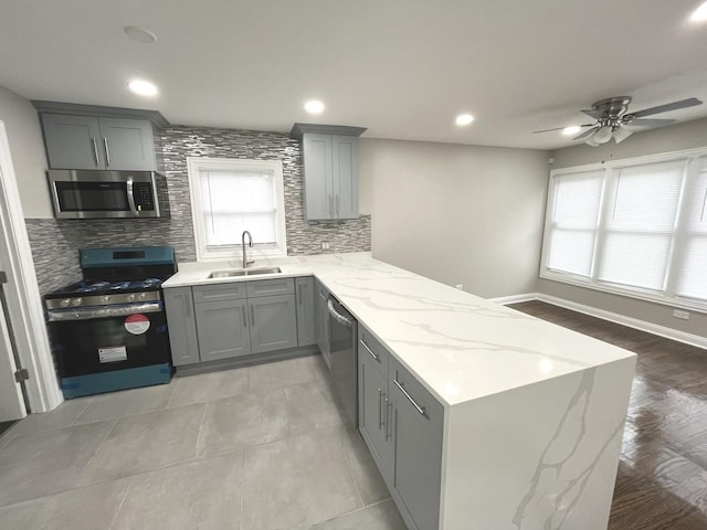 kitchen featuring kitchen peninsula, appliances with stainless steel finishes, decorative backsplash, and sink