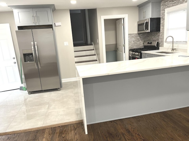 kitchen with kitchen peninsula, stainless steel appliances, gray cabinetry, and sink