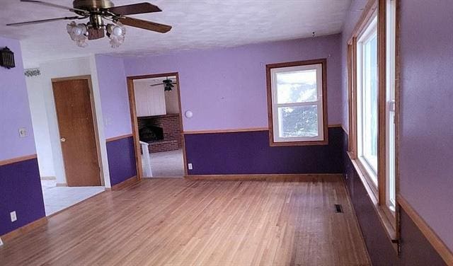 spare room featuring ceiling fan, a fireplace, and hardwood / wood-style flooring