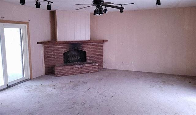 unfurnished living room featuring ceiling fan, plenty of natural light, and a fireplace