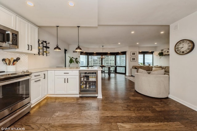 kitchen with white cabinetry, beverage cooler, decorative light fixtures, and appliances with stainless steel finishes