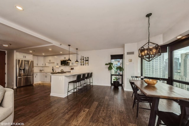 interior space with a breakfast bar, hanging light fixtures, kitchen peninsula, white cabinetry, and stainless steel appliances