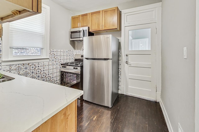 kitchen featuring dark wood-type flooring, light stone countertops, and appliances with stainless steel finishes