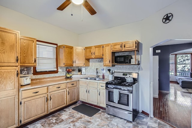 kitchen featuring light brown cabinetry, backsplash, ceiling fan, sink, and stainless steel gas stove