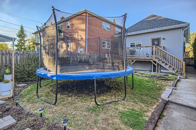 back of property with a trampoline and a wooden deck