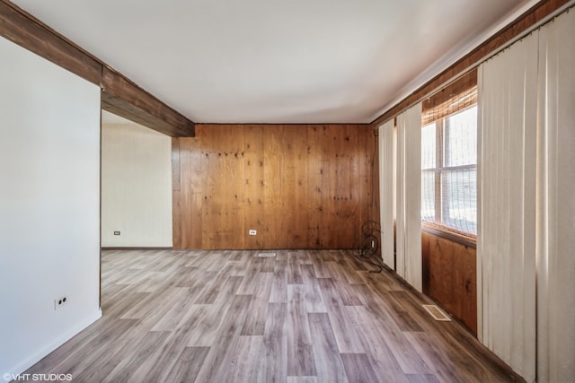 unfurnished room with light hardwood / wood-style flooring and wood walls