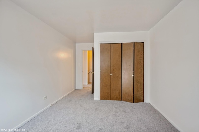 unfurnished bedroom featuring light colored carpet and a closet