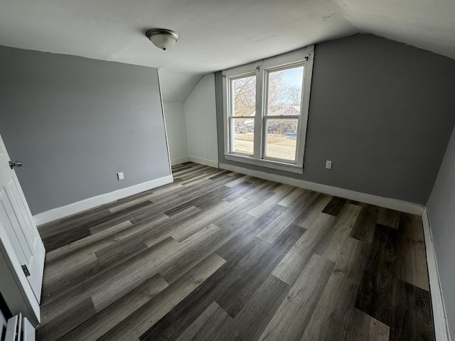 additional living space with dark wood-type flooring and vaulted ceiling