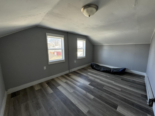 bonus room with vaulted ceiling and dark wood-type flooring