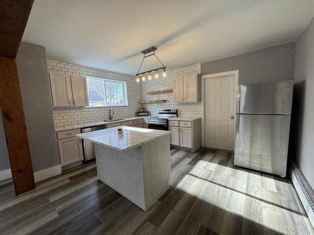 kitchen featuring a center island, a baseboard heating unit, sink, decorative light fixtures, and stainless steel appliances