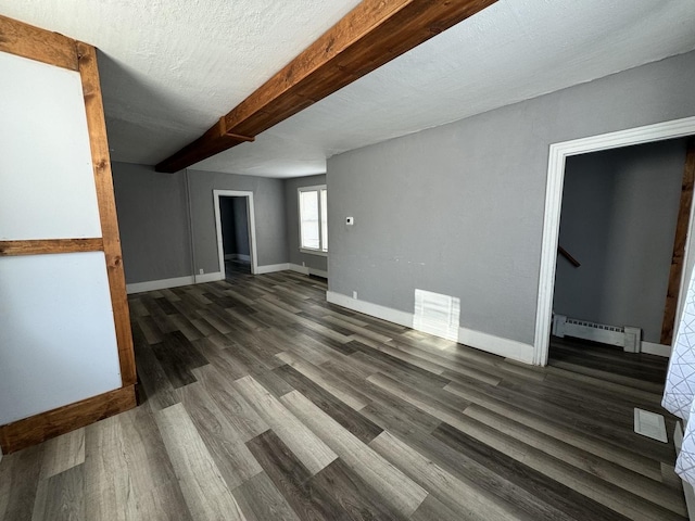 unfurnished living room with a textured ceiling, dark hardwood / wood-style flooring, baseboard heating, and beam ceiling