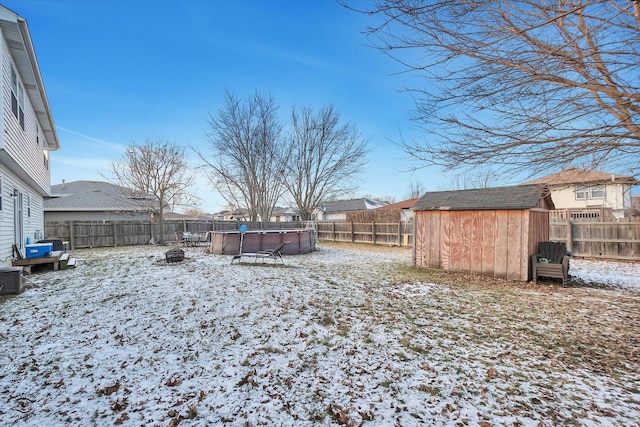 yard covered in snow with a fenced in pool and a shed