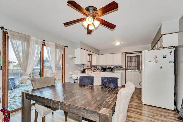 dining space with ceiling fan and light wood-type flooring