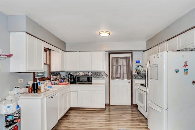 kitchen featuring decorative backsplash, light wood-type flooring, white appliances, sink, and white cabinets