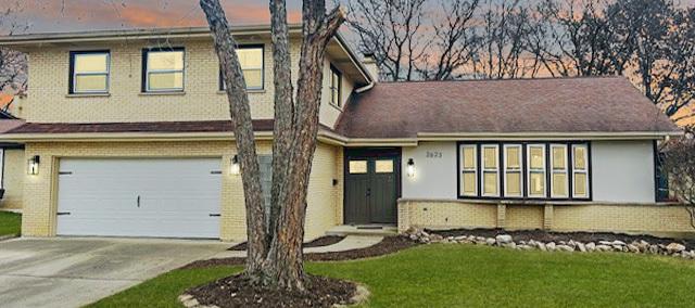 view of front of home with a garage and a lawn