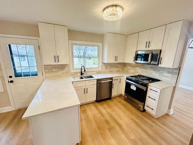 kitchen featuring white cabinetry, sink, stainless steel appliances, a chandelier, and light wood-type flooring