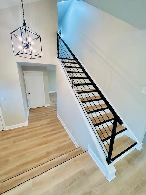 staircase featuring hardwood / wood-style flooring, a high ceiling, and a chandelier