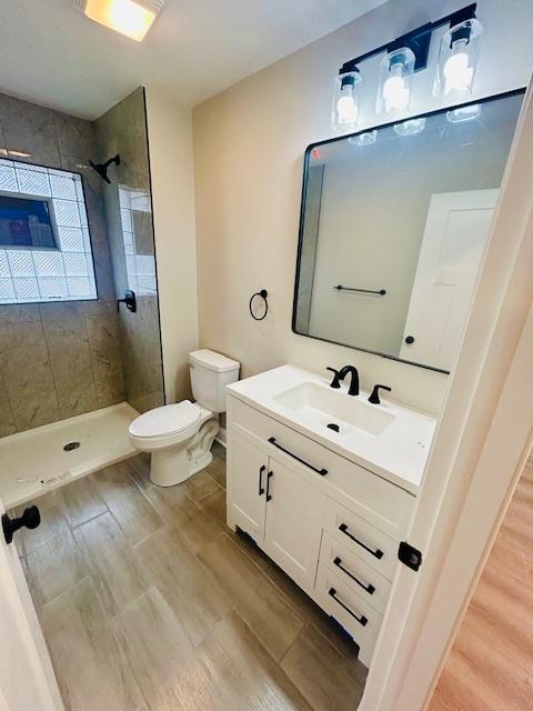 bathroom with vanity, toilet, and tiled shower