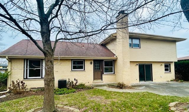 rear view of property featuring central AC unit, a patio area, and a lawn